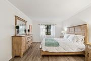 Clearwater apartment for rent - A bedroom with a large bed, a dresser, and a mirror at Hampton Apartments, Clearwater, FL, 33759