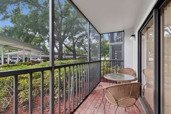 A balcony with a table and chairs overlooking a parking lot.