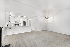 Santa Rosa apartment for rent - A spacious kitchen with white cabinetry and living area with and neutral carpet.