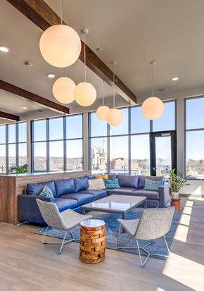 Rochester apartment for rent - a lounge area with blue couches and chairs and large windows