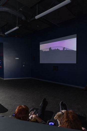 A group of people are sitting in a dark room watching a movie on a screen