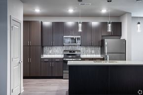 Independence apartment for rent - A modern kitchen with dark wood cabinets and stainless steel appliances. at Trinity Woods Apartments, Independence, MO