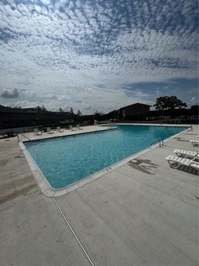 Dundalk apartment for rent - A large outdoor swimming pool with sun loungers and a cloudy sky.