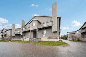 Anchorage apartment for rent - A large grey building with a balcony and a smaller building to its left.