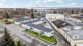 Anchorage apartment for rent - A large white building with a black roof is surrounded by other buildings and trees.
