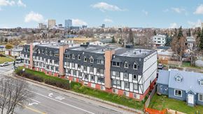Anchorage apartment for rent - A large building with a red and white facade sits in the foreground of a city street.