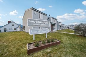 Kenai apartment for rent - A sign for Woodridge Apartments stands in front of the building.