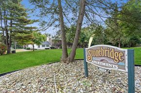Ellington apartment for rent - a sign for stonebridge apartments in front of a lawn and trees at Stonebridge, Ellington, CT