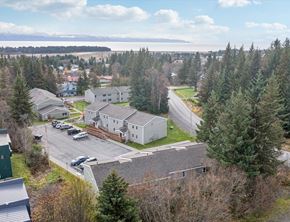 Homer apartment for rent - A large white building surrounded by trees and a parking lot.