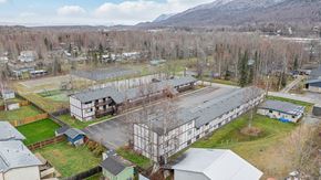 Eagle River apartment for rent - A large building with a metal roof is surrounded by smaller buildings and trees.