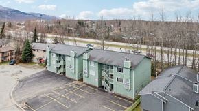 Eagle River apartment for rent - A parking lot in front of a green building with a mountain in the background.