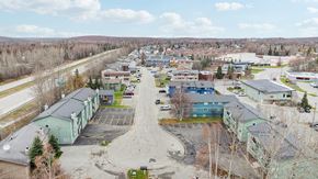 Eagle River apartment for rent - A parking lot is surrounded by buildings and trees.
