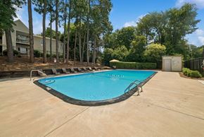 Charlotte apartment for rent - A small pool surrounded by trees and a building.