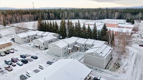 North Pole apartment for rent - A snowy landscape with a building and cars.