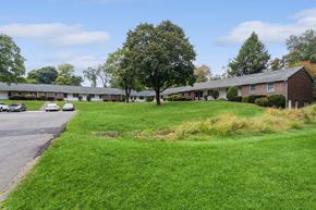 Ellington apartment for rent - the front of a building with a green lawn and a parking lot