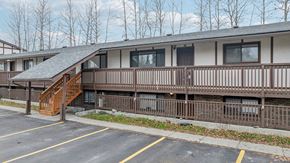 Eagle River apartment for rent - A parking lot in front of a building with a wooden staircase.