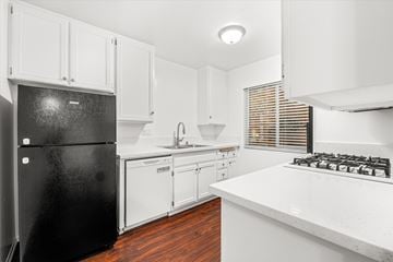 Ventura townhouse for rent - A black refrigerator sits in a kitchen with white cabinets and a white countertop.