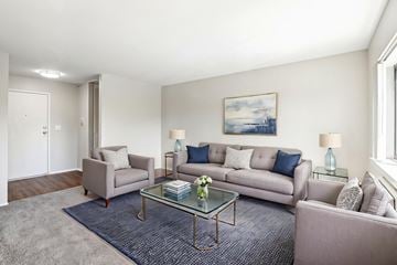 Aurora apartment for rent - A living room with a grey couch, a grey armchair, a glass coffee table and a painting on the wall.