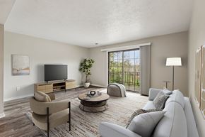 Pittsburgh apartment for rent - A living room with a grey couch, a chair, a coffee table, a television, and a potted plant.