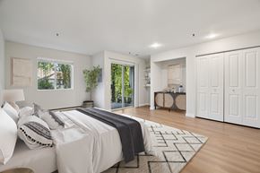 Milwaukie apartment for rent - A bedroom with a large bed and a view of trees through the window.