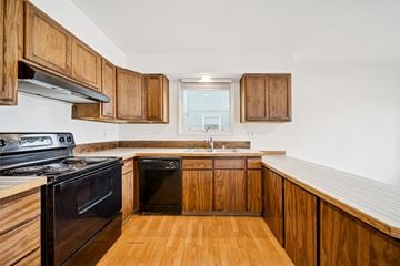 Eagle River apartment for rent - A kitchen with wooden cabinets and black appliances.