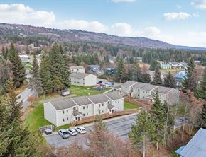 Homer apartment for rent - A large white building surrounded by trees and a parking lot.