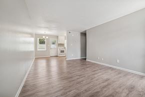 Charlotte apartment for rent - A spacious room with wood flooring and a kitchen in the background.