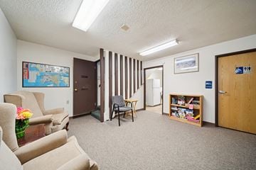 Kenai apartment for rent - A living room with a couch, chair, and a small table with a vase of flowers on it.