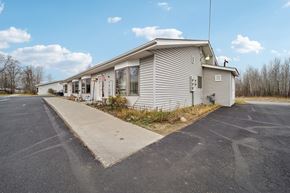 Soldotna apartment for rent - A house with a grey siding and a white roof is surrounded by a parking lot.