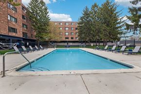 Aurora apartment for rent - A swimming pool in front of a brick building with trees around.