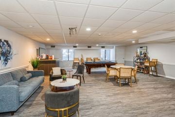 Pittsburgh apartment for rent - A spacious living room with a grey sofa, a coffee table, and a dining table set up with chairs.