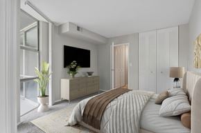 St. Charles apartment for rent - A bedroom with a large bed and a dresser with a plant on top.