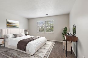 Pittsburgh apartment for rent - A bedroom with a large bed and a desk with a plant on it.