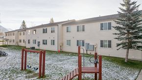 Palmer apartment for rent - A playground with a swing set and a basketball hoop in front of apartment buildings.