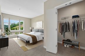 Pittsburgh apartment for rent - A bedroom with a large bed and a closet with clothes hanging.