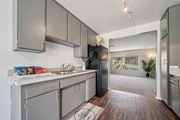 Riverside apartment for rent - A kitchen with a black refrigerator and wooden floors.