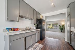 Riverside apartment for rent - A kitchen with a black refrigerator and wooden floors.