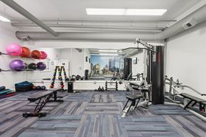 Pittsburgh apartment for rent - A gym with a variety of equipment including a bench, and a weight rack.