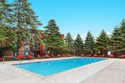 Eden Prairie apartment for rent - a swimming pool with red chairs around it in front of a building