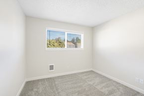 Milwaukie apartment for rent - A room with a window showing a view of trees and a building outside.