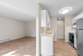Beaverton apartment for rent - A kitchen with white cabinets and a refrigerator with a view of the living room