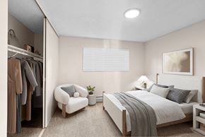 Beaverton apartment for rent - A bedroom with a large bed, a chair, and a closet with clothes.