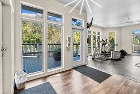 Milwaukie apartment for rent - A spacious room with a gym setup and a view of a deck through the sliding glass doors.