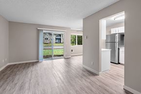 Beaverton apartment for rent - A spacious room with a view of a green lawn and a building through the sliding glass door.