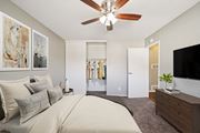 Riverside apartment for rent - A bedroom with a large bed, a ceiling fan, and a television.