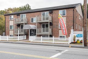 Worcester apartment for rent - an apartment building with a red brick facade and a sign in front at Flats at Merrill Pond, Worcester