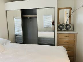 Salinas apartment for rent - A bedroom with a white bed, a wooden dresser, and a mirror.