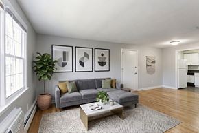 Manchester apartment for rent - A living room with a grey couch, a coffee table, and three framed pictures on the wall.