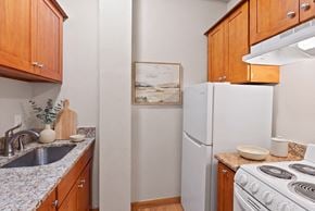 Portland apartment for rent - A kitchen with a white refrigerator, stove, and wooden cabinets.