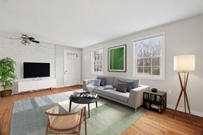 Ellington apartment for rent - A living room with a grey couch, a black coffee table, a white television, a ceiling fan, and a green rug.